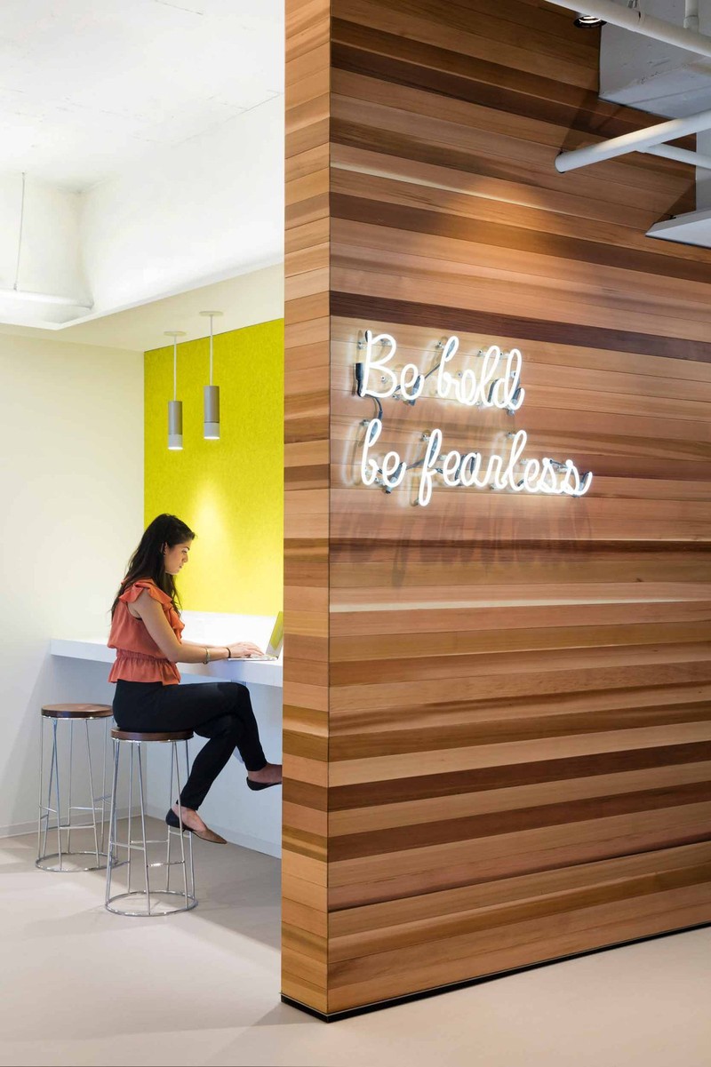 A woman works on her laptop in a private workspace next to a sign that reads 